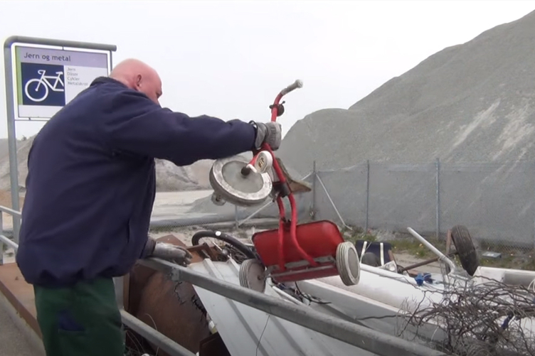 Billede af medarbejder der fisker en trehjulet cykel op af container